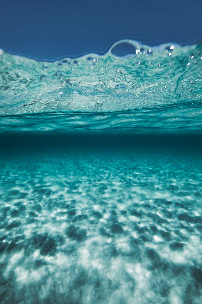 Entre deux bleus, photographie aquatique d'art à fleur d'eau au-dessus d'un fond de sable